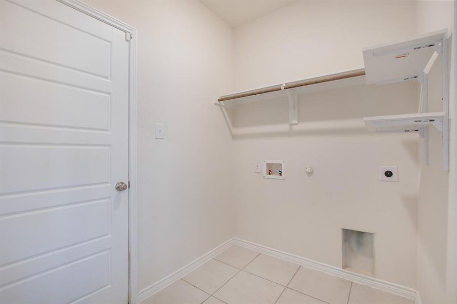 Clothes washing area with hookup for a gas dryer, hookup for a washing machine, light tile patterned floors, and electric dryer hookup