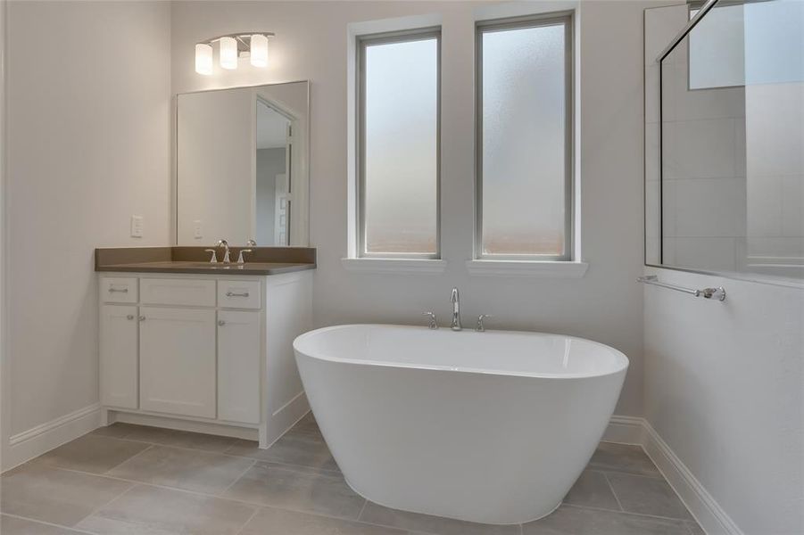 Bathroom with a wealth of natural light, a tub, tile patterned floors, and vanity