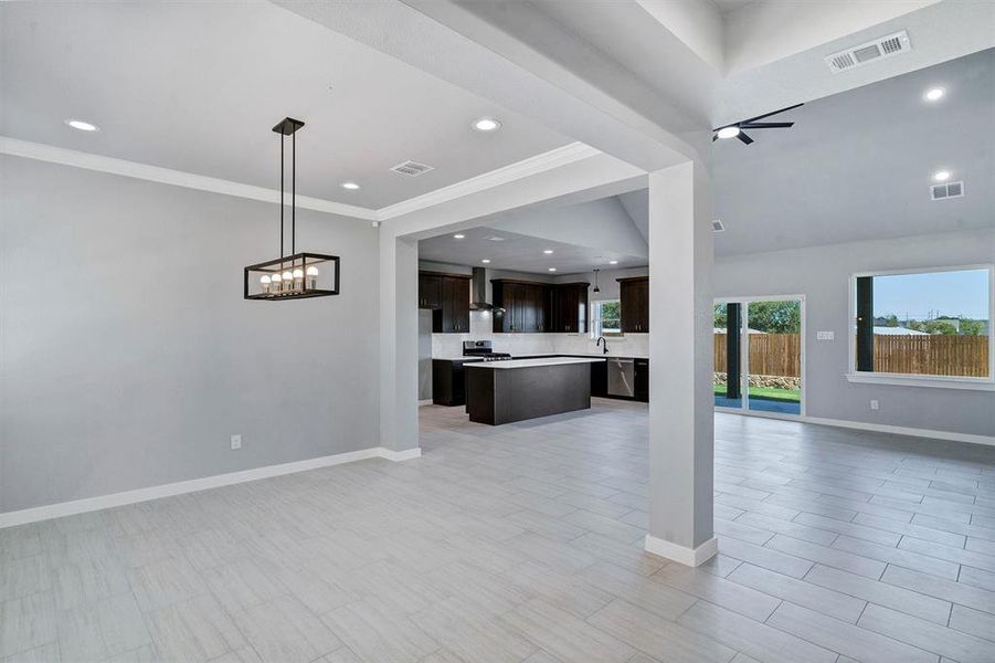 Unfurnished living room featuring crown molding, sink, and a chandelier