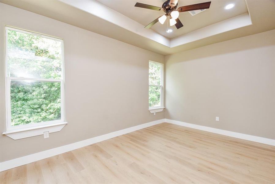 Primary Bedroom with Tray Ceiling, LED Lighting, and Ceiling Fan.