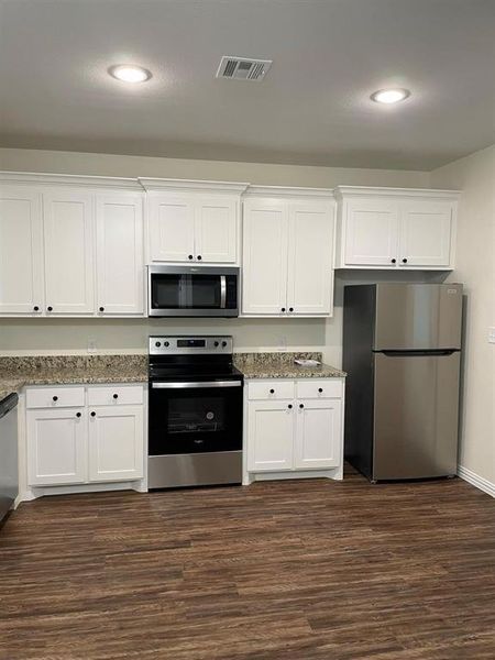 Kitchen with white cabinetry, dark wood-type flooring, and appliances with stainless steel finishes