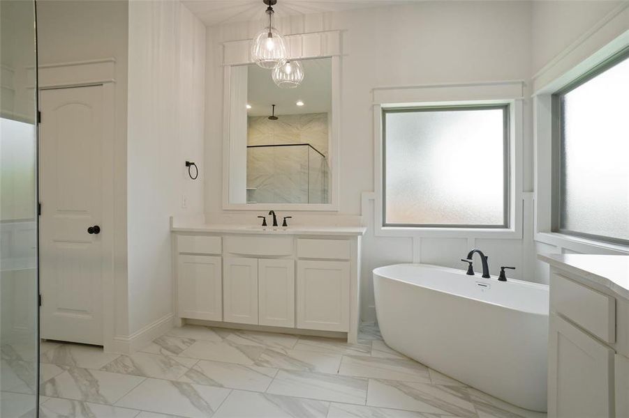 Bathroom featuring tile floors, vanity, and a bath to relax in