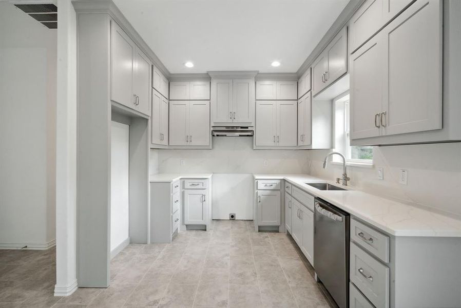 Kitchen featuring light tile patterned floors, sink, stainless steel dishwasher, gray cabinets, and light stone countertops