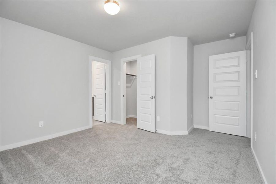 Secondary bedroom features plush carpeting, large windows that let in plenty of natural light, bright paint, and spacious closets.