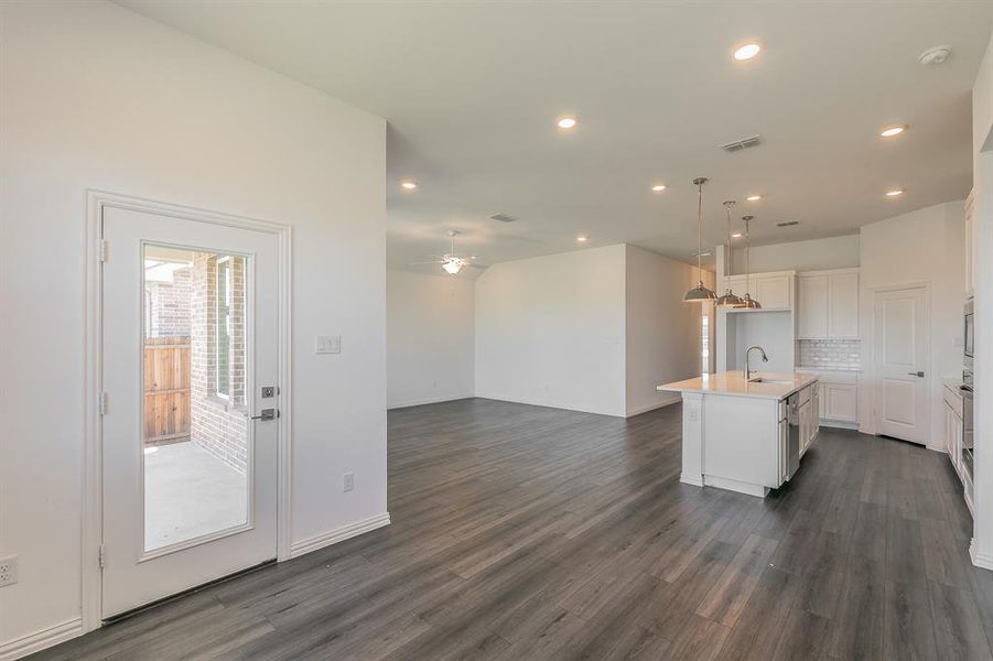 Kitchen featuring an island with sink, white cabinets, ceiling fan, and dark wood-type flooring