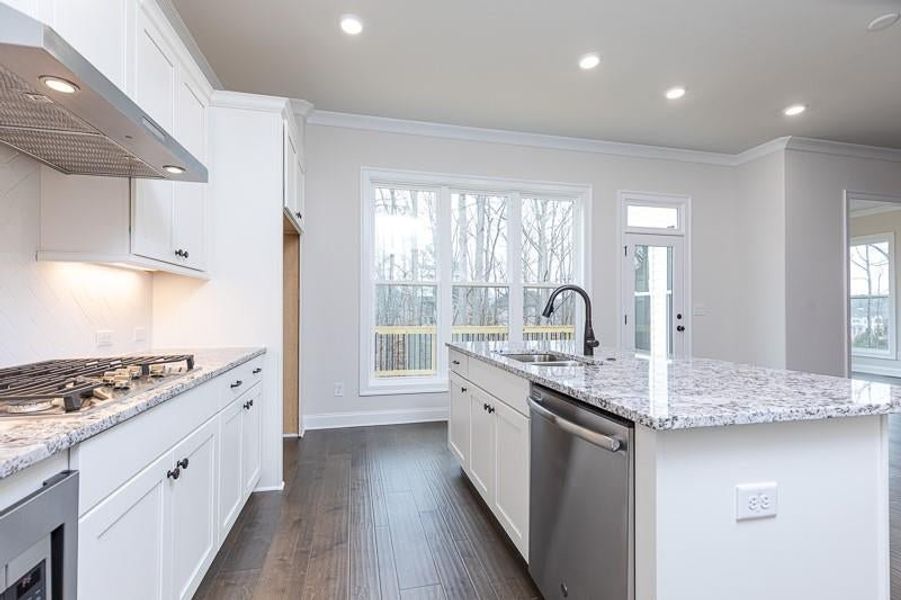 Kitchen with stainless steel finishes, sink, backsplash, and a center island with sink is perfect for entertaining and visiting with friends and family.  Photo not actual home, but previously built Mansfield plan.