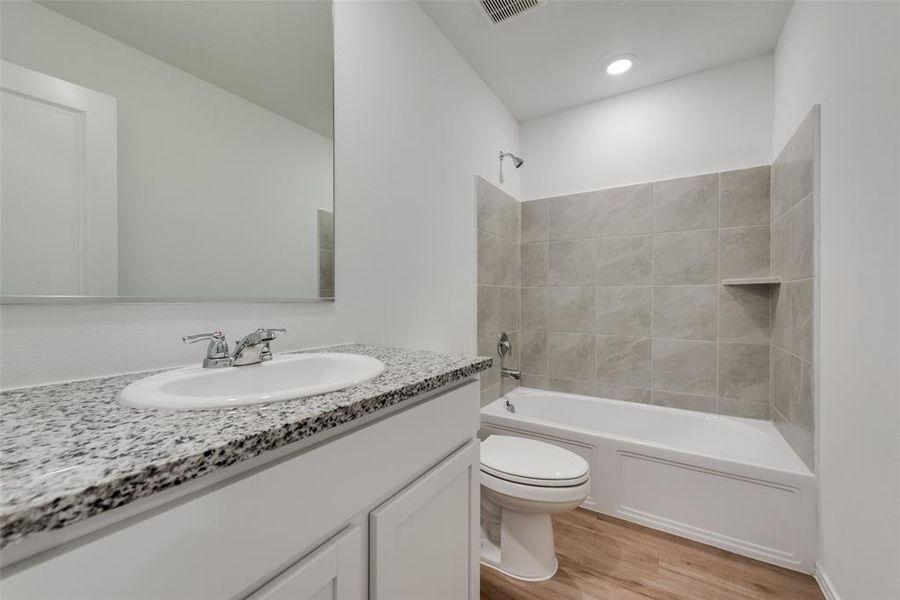 Full bathroom featuring vanity, tiled shower / bath, toilet, and wood-type flooring