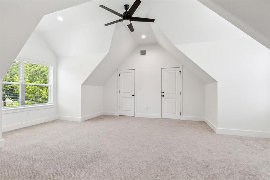 Playroom with ceiling fan, vaulted ceiling, and light colored carpet