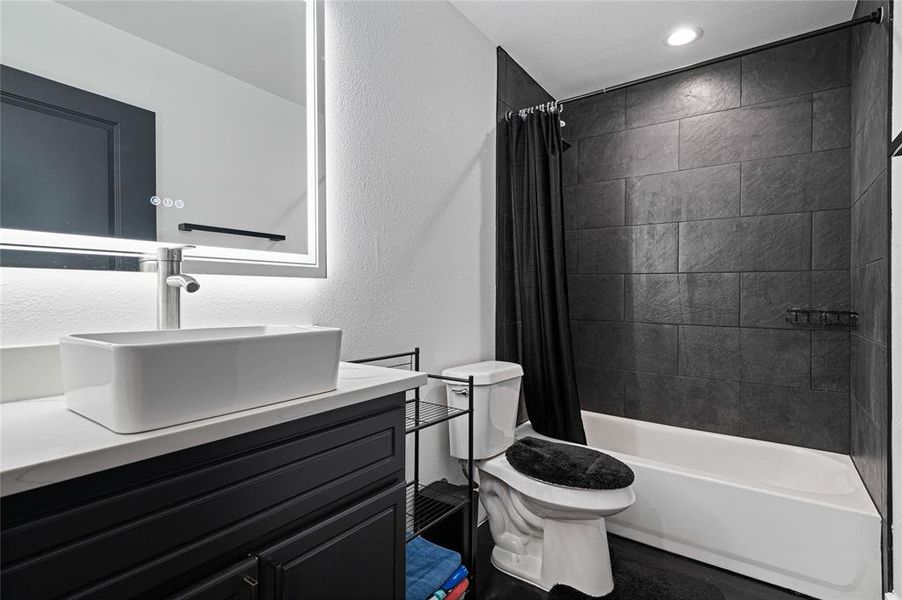 Full bathroom with shower / bath combo with shower curtain, oversized vanity, and toilet