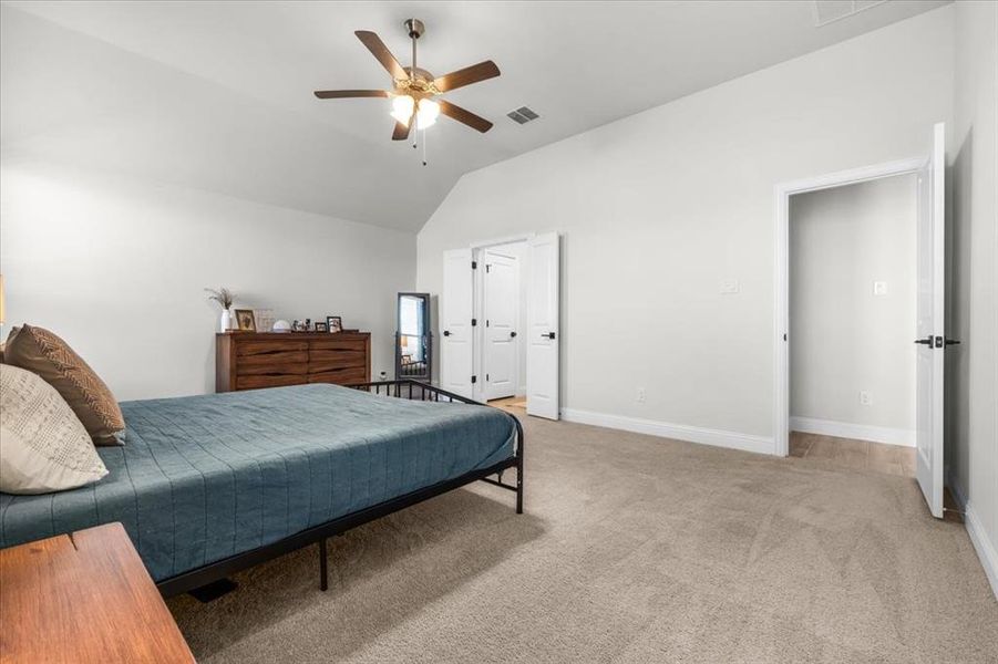 Carpeted bedroom with ceiling fan and vaulted ceiling