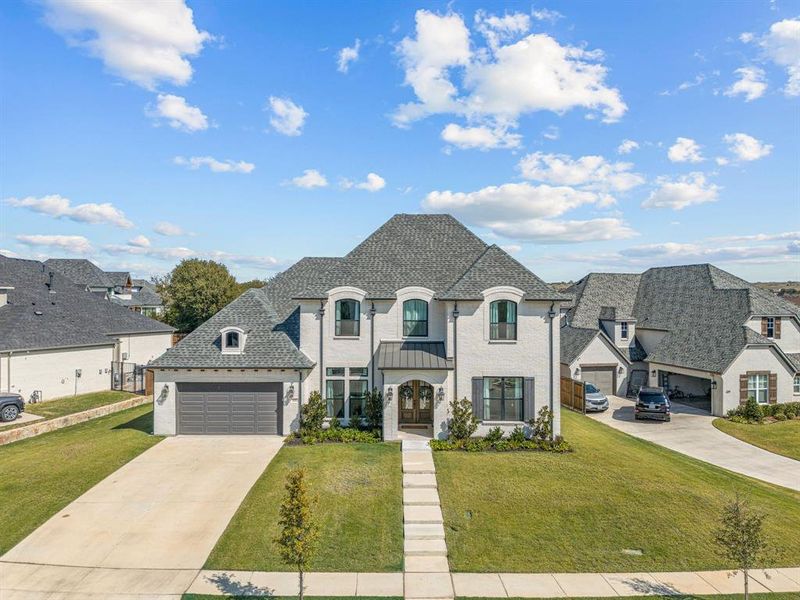 French country inspired facade with a balcony, a garage, and a front lawn