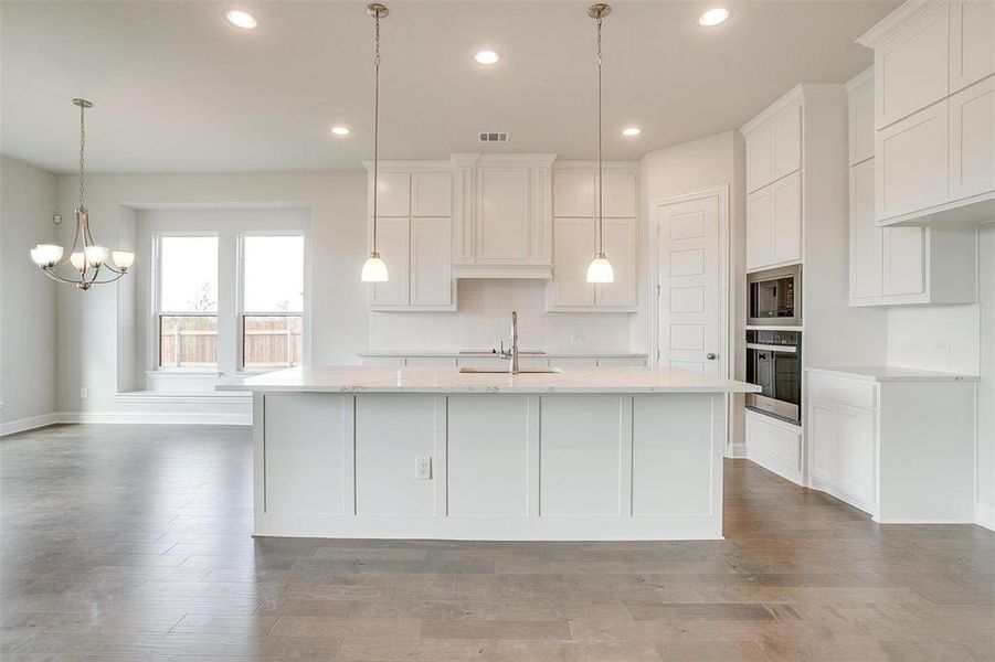 Kitchen featuring appliances with stainless steel finishes, white cabinetry, sink, and a center island with sink