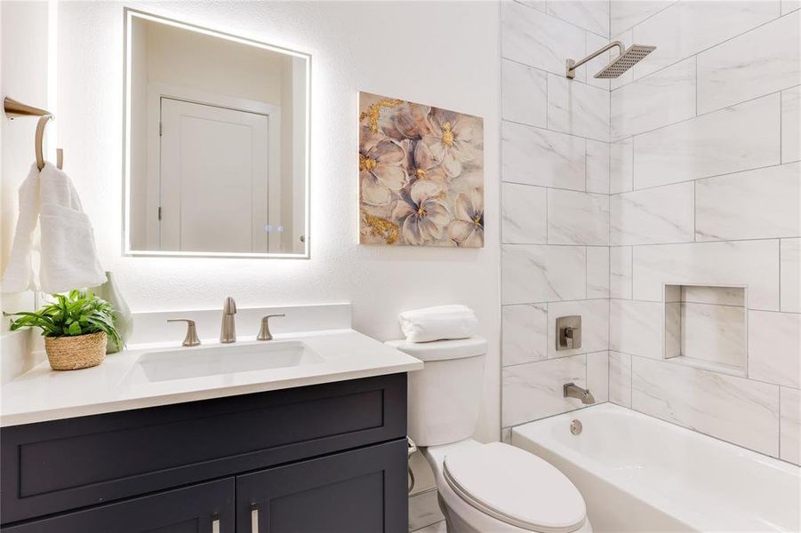 Full bathroom featuring tiled shower / bath combo, vanity, and toilet