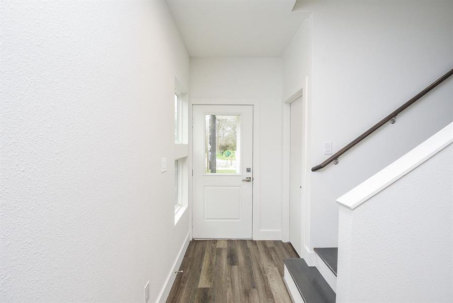 Cool, neutral walls and good looking vinyl flooring fill the front entry, in this inside view; with the conveniently placed staircase.