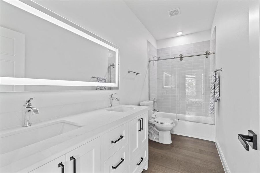 Full bathroom featuring hardwood / wood-style floors, vanity, toilet, and tiled shower / bath