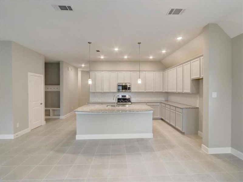 Modern kitchen with stylish cabinets, granite countertop, chic backsplash, stainless steel appliances, and contemporary fixtures