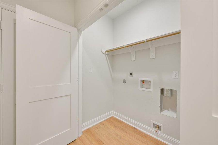 This is an in-house laundry closet with connections for full-sized washer and dryer, featuring a shelf for storage.