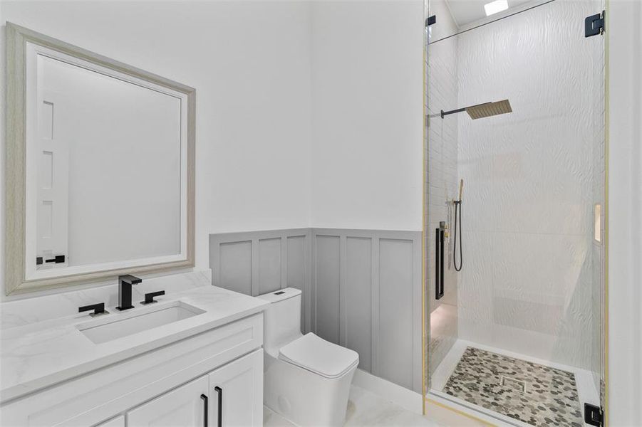 Bathroom featuring a shower with door, oversized vanity, and toilet