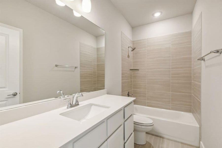 Full bathroom with tiled shower / bath, vanity, and toilet