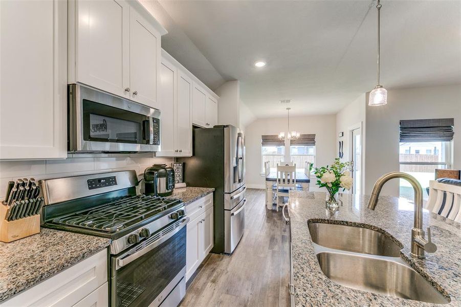 Kitchen featuring appliances with stainless steel finishes, a healthy amount of sunlight, sink, and a notable chandelier