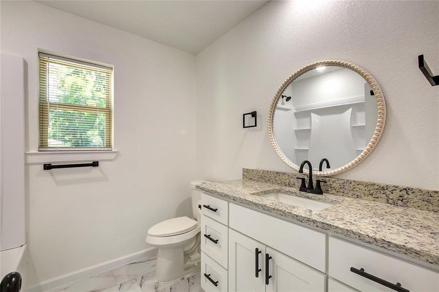 Bathroom featuring tile flooring, toilet, and granite vanity