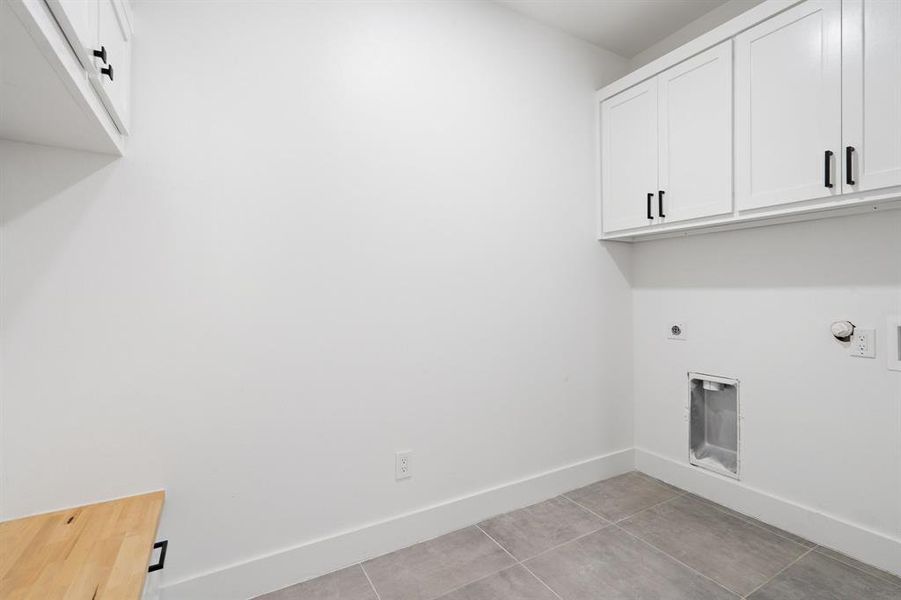 Laundry area featuring cabinets, light tile patterned flooring, and electric dryer hookup