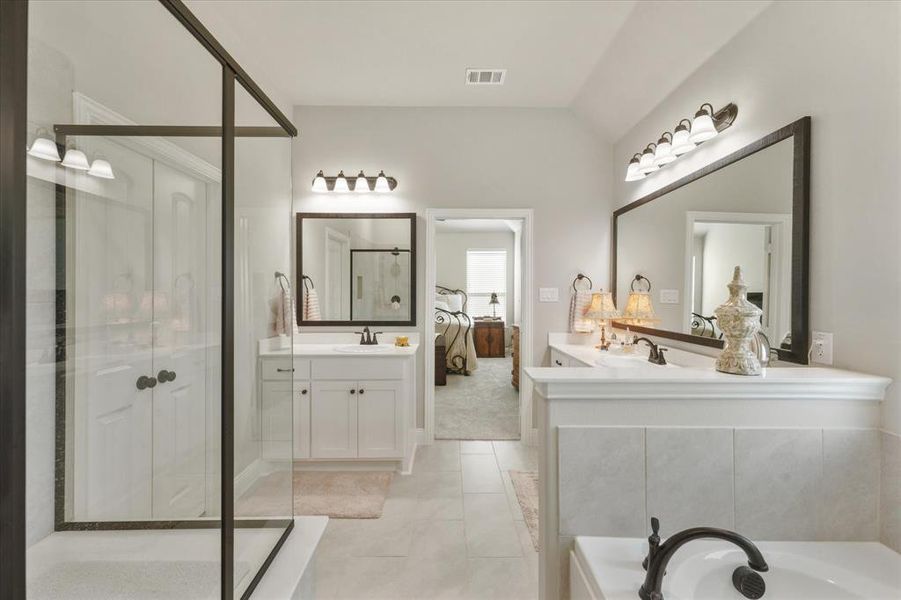 Bathroom with vanity, lofted ceiling, tile patterned floors, and separate shower and tub