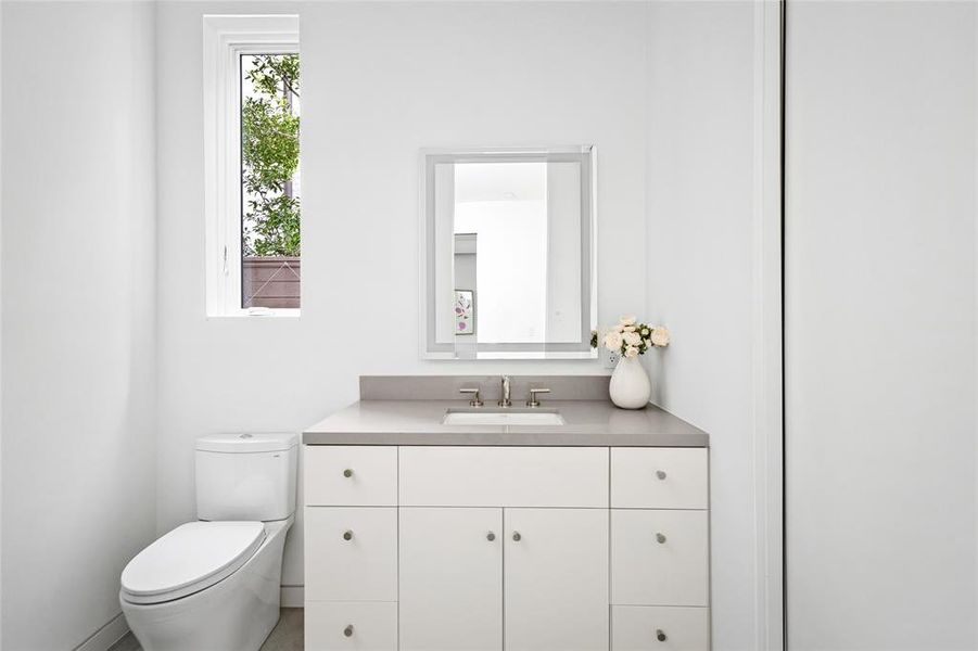 A clean and bright ensuite bath located off the study features a modern vanity with sleek gray quartz counters and ample storage. The natural light from the small window adds to the airy feel, making this space both functional and refreshing.