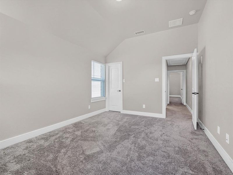 Unfurnished bedroom featuring carpet and vaulted ceiling