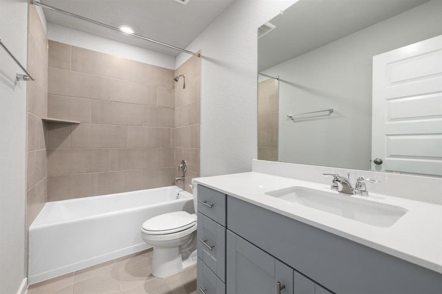 Secondary bathroom features double sinks, Quartz countertops, neutral paint, shower/tub combo with tile surround, large mirror, tile floors, sleek fixtures and modern finishes, plenty of space to accommodate any visiting family or guests.