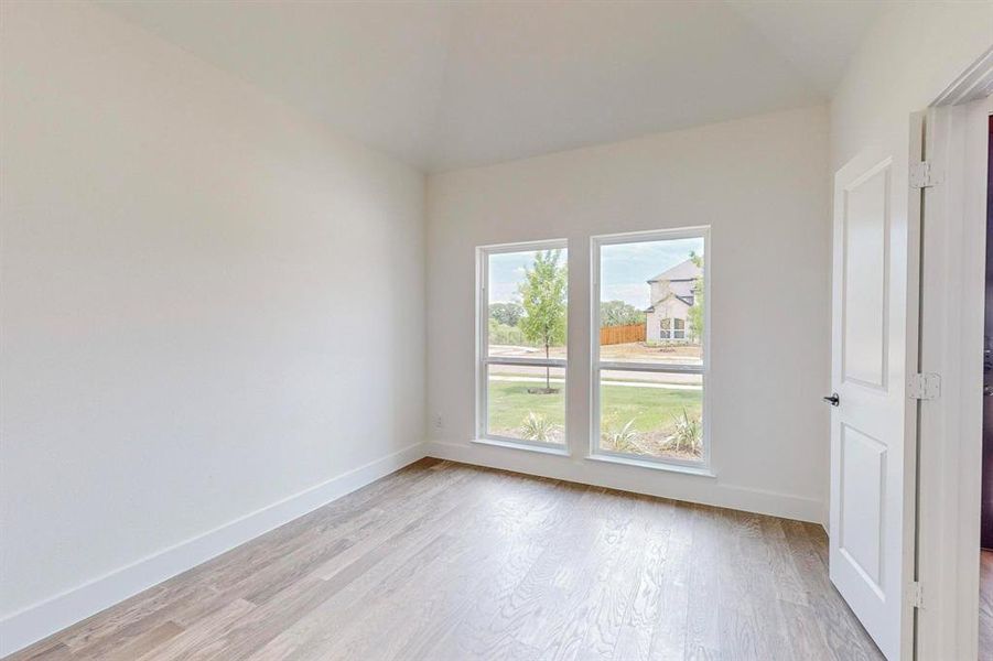 Empty room with light hardwood / wood-style flooring and vaulted ceiling