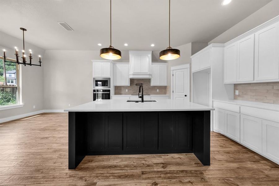 Kitchen with black appliances, backsplash, and light hardwood / wood-style flooring