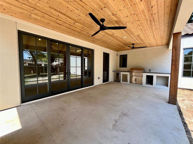 Unfurnished living room featuring wood ceiling, ceiling fan, a wealth of natural light, and concrete floors