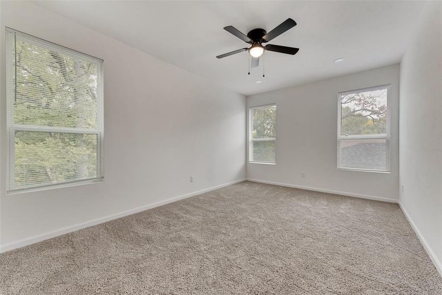 Empty room with ceiling fan, carpet floors, and a healthy amount of sunlight