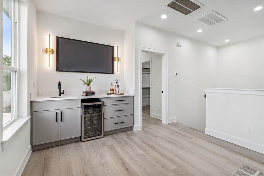 Elevate your entertaining with a stunning second-floor wet bar, featuring a wine cooler, stylish black accent wall, and ample space for your TV. This sophisticated focal point is perfect for hosting guests or unwinding in style.