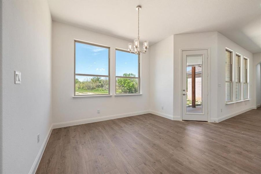 Spare room with a notable chandelier and hardwood / wood-style floors