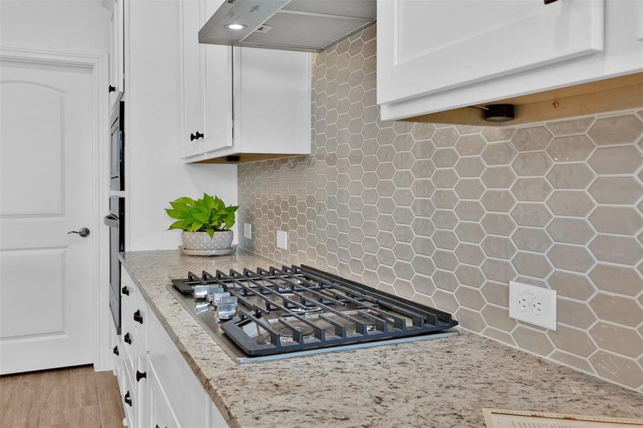 Admire this gorgeous upgraded backsplash and gas burner cooktop.
