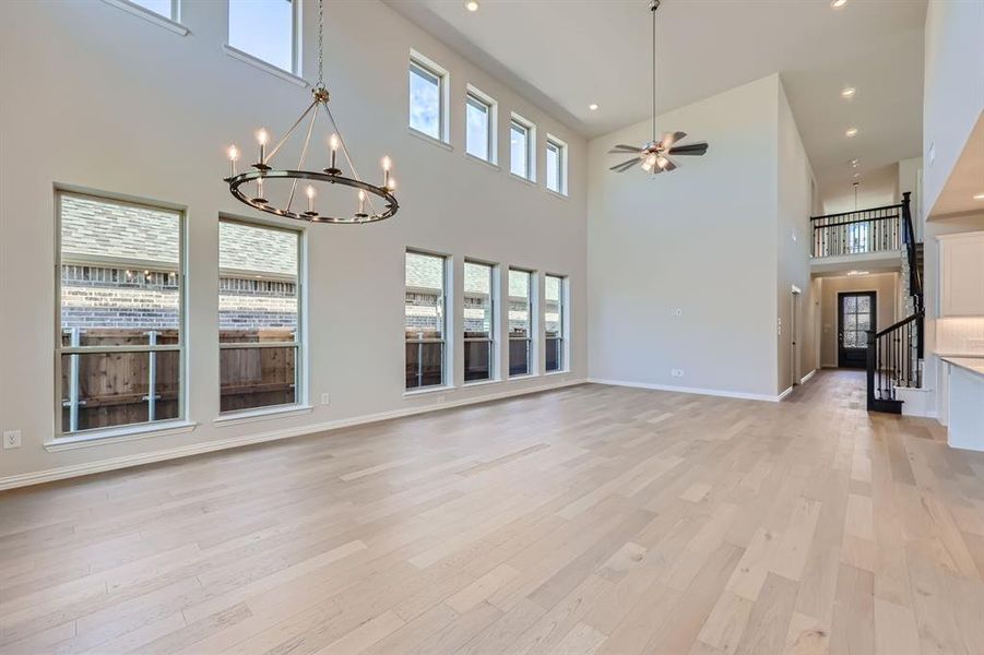 Living room featuring a wealth of natural light, light wood-type flooring, and a towering ceiling