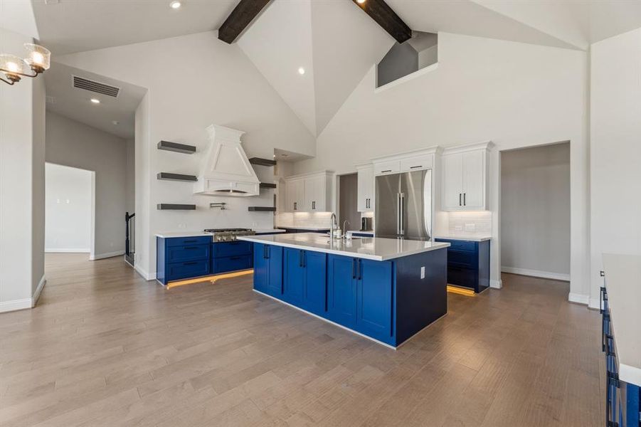 Kitchen featuring appliances with stainless steel finishes, white cabinetry, high vaulted ceiling, blue cabinetry, and beam ceiling