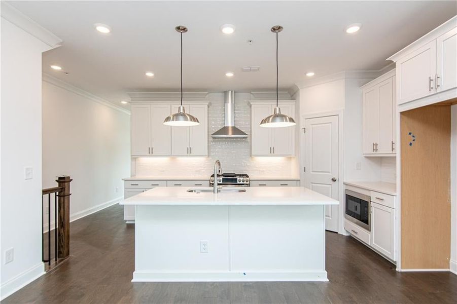 Kitchen with wall chimney range hood, stainless steel appliances, white cabinets, dark hardwood / wood-style floors, and a kitchen island with sink, not the actual unit