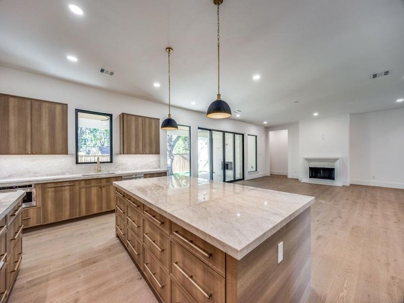 Kitchen with light hardwood / wood-style flooring, hanging light fixtures, a spacious island, and a healthy amount of sunlight