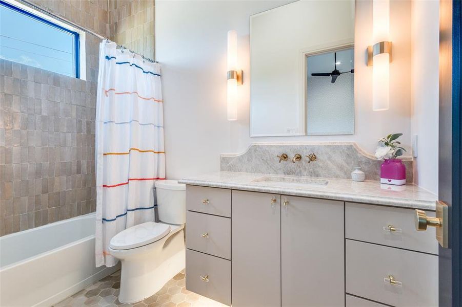 Full bathroom with ceiling fan, oversized vanity, shower / tub combo with curtain, tile floors, and toilet