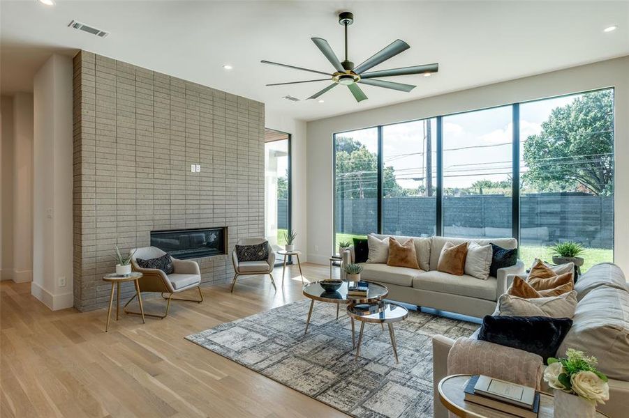 Living room with light wood-type flooring, a fireplace, and ceiling fan