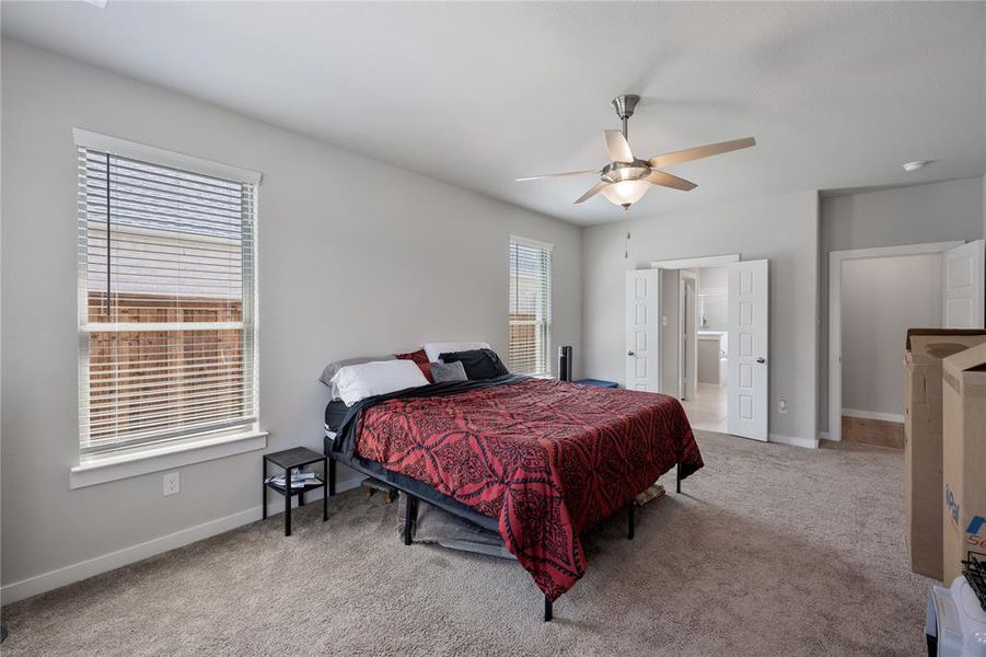 Carpeted bedroom featuring connected bathroom and ceiling fan