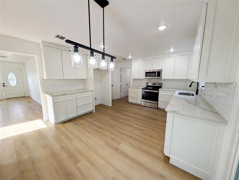 Kitchen featuring white cabinetry, sink, light hardwood / wood-style flooring, and stainless steel appliances