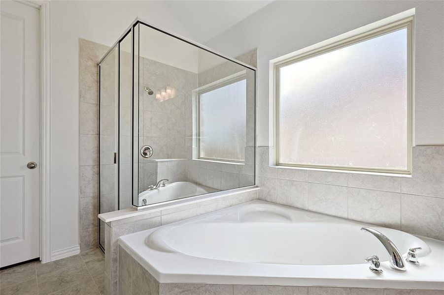 Bathroom with tile patterned floors, a wealth of natural light, and shower with separate bathtub