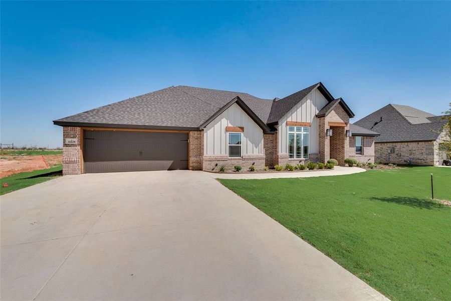 View of front of property featuring a front yard and a garage