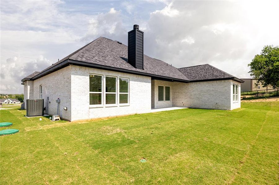 Back of property featuring a yard and central AC