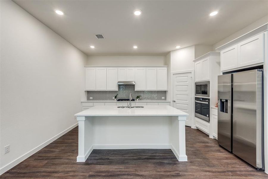 Kitchen with decorative backsplash, stainless steel appliances, dark hardwood / wood-style flooring, and sink