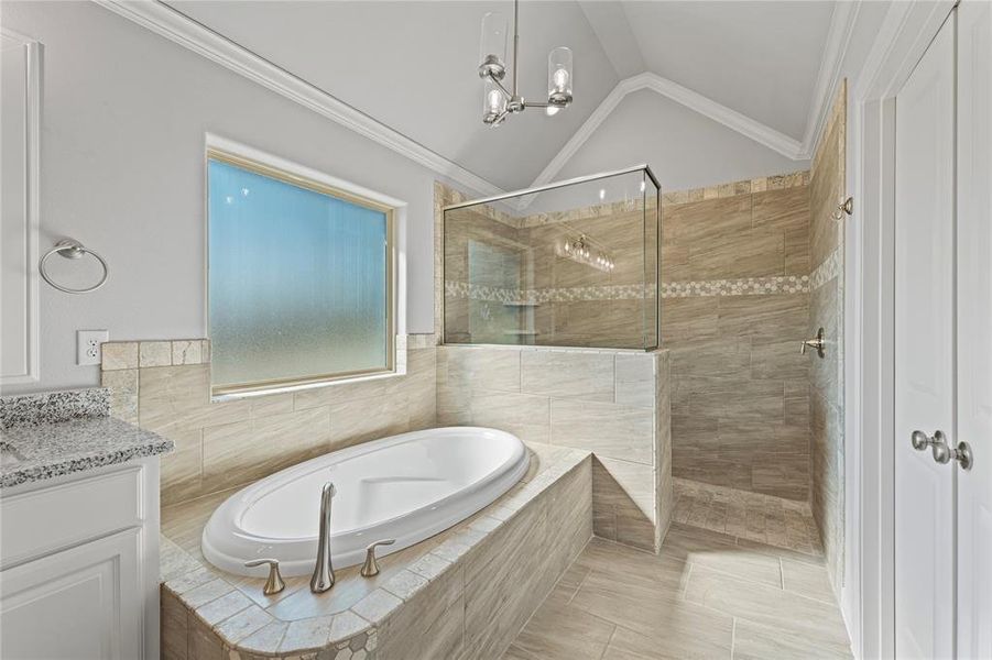 Bathroom with tile patterned floors, ornamental molding, vaulted ceiling, vanity, and shower with separate bathtub